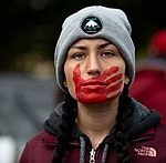 Woman with red handprint on her mouth, a symbol of solidarity with missing and murdered Indigenous women and girls