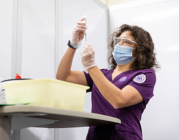 Masked care provider filling a syringe