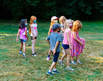 A group of masked children playing in the grass.