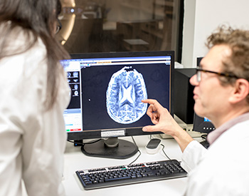 Closeup of two individuals discussing a scan image on a computer screen.