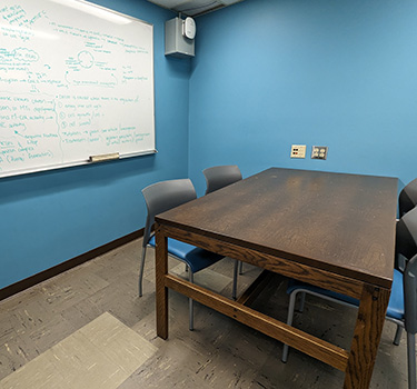 Room with a table, four chairs and a whiteboard.