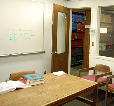 Study room with a door, window into the library, whiteboard, and a table and chairs.