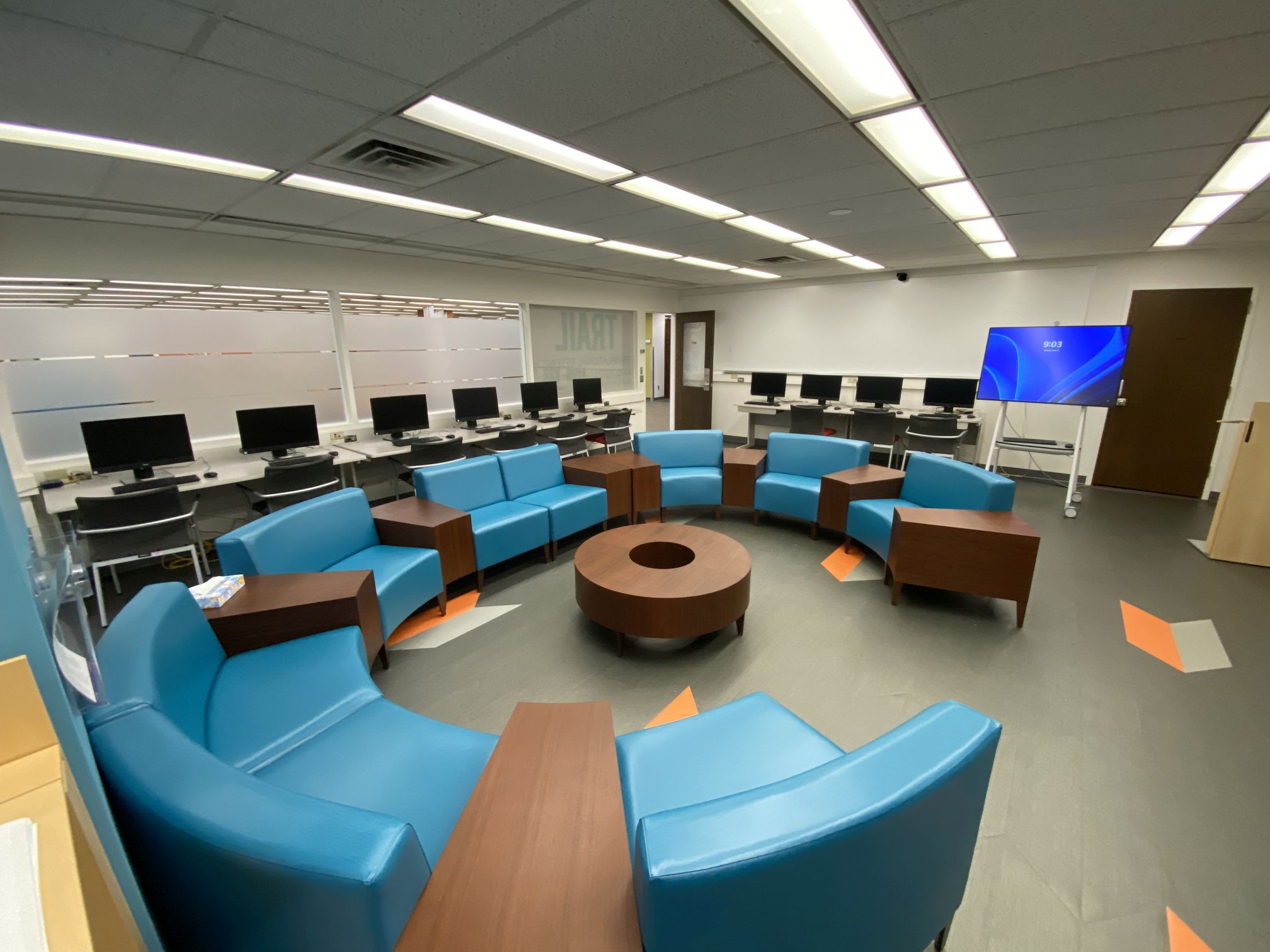 Photo of Room T216 showing campfire seating, a Microsoft Hub screen, and 10 computers