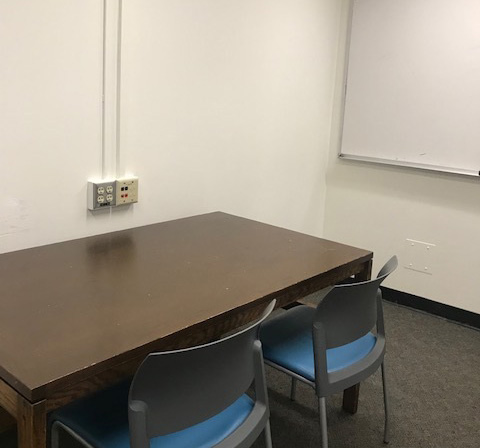 Study room with a wood table with two chairs around it and a whiteboard on the wall