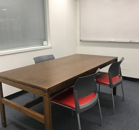 Study room with a wood table with three chairs around it and a whiteboard on the wall